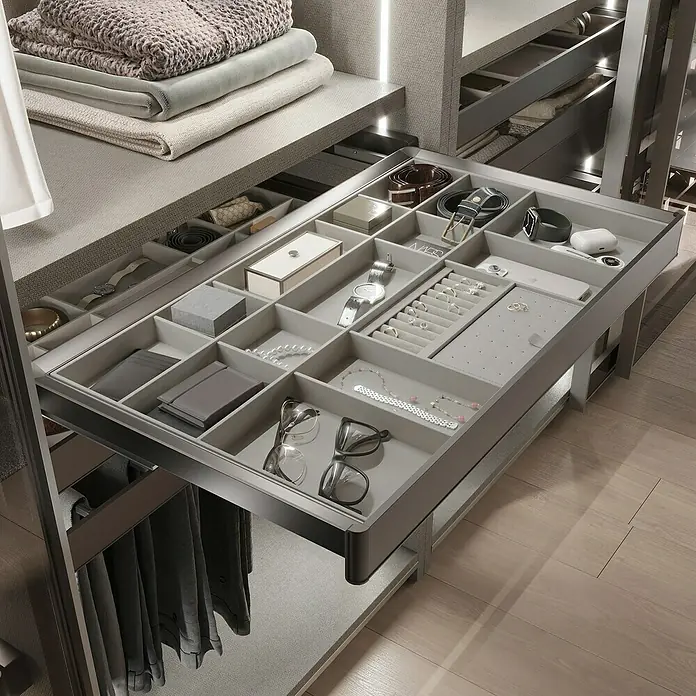Emuca Schrank-Organisator Quartz - Breitenverstellung: 562 mm - 688 mm, Höhe: 66 mm, Traglast: 30 kg - Ausziehbarer Schmuckschrank mit Fächern für Uhren, Ringe, Gürtel und Brillen, alles ordentlich in hellgrauen Einsätzen aufbewahrt.