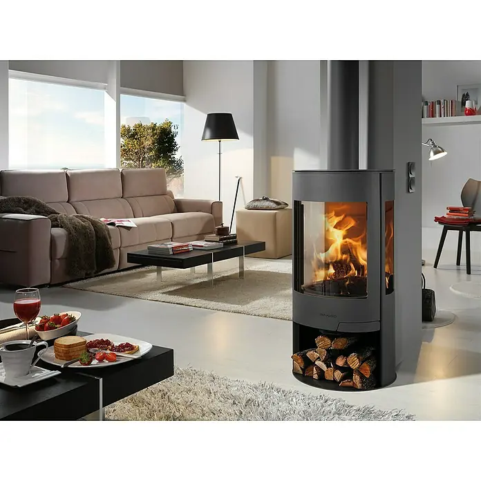 Panadero Kaminofen Helsinki Ecodesign - 8 kW, Raumheizvermögen: 240 m³, Material Verkleidung: Stahl, Schwarz Metallic - Moderne Kaminofen-Einrichtung mit gemütlichem Feuer und Holzscheiten. Das elegante Design des Ofens sorgt für eine behagliche Atmosphäre im Raum.