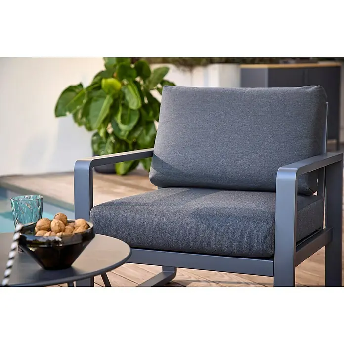 Sunfun Maja Loungesessel - B x T x H: 76 x 76 x 74,5 cm, Aluminium, Olefin, Night-Grey - Nahaufnahme eines grauen Sessels mit Aluminiumrahmen, neben einem Tisch mit Nüssen und einem Getränk.