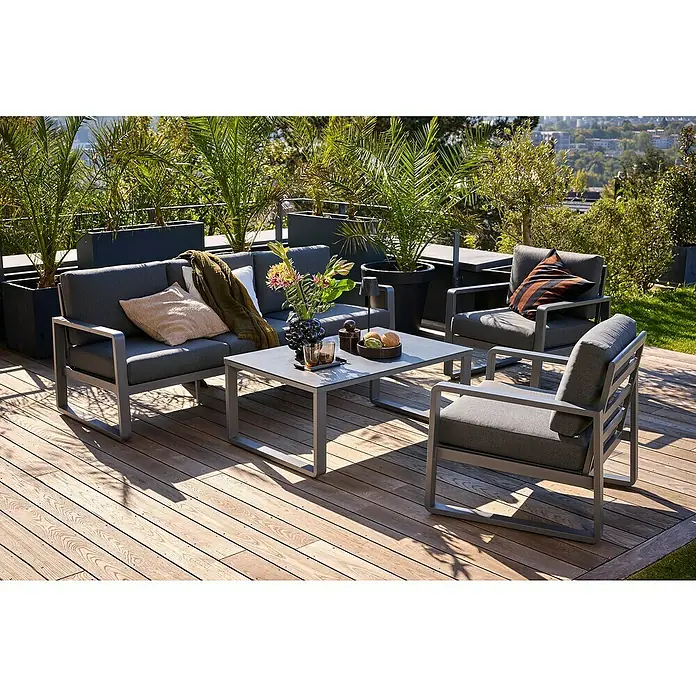 Sunfun Maja Loungemöbel-Set - 4 -tlg., Aluminium, Sicherheitsglas, Olefin, Zwei Sessel, Night-Grey - Outdoor-Lounge-Set auf Holzterrasse mit Sofa, Sesseln und Tisch, umgeben von Pflanzenkübeln für entspannte Stunden im Freien.