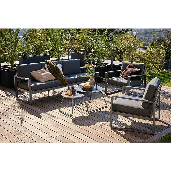 Sunfun Maja Loungemöbel-Set - 5 -tlg., Aluminium, Stahl, Olefin, Night-Grey - Einladende Gartenmöbel-Gruppe mit grauem Sofa, Sesseln und Tischen auf einer Holzterrasse mit üppiger Bepflanzung im Hintergrund.