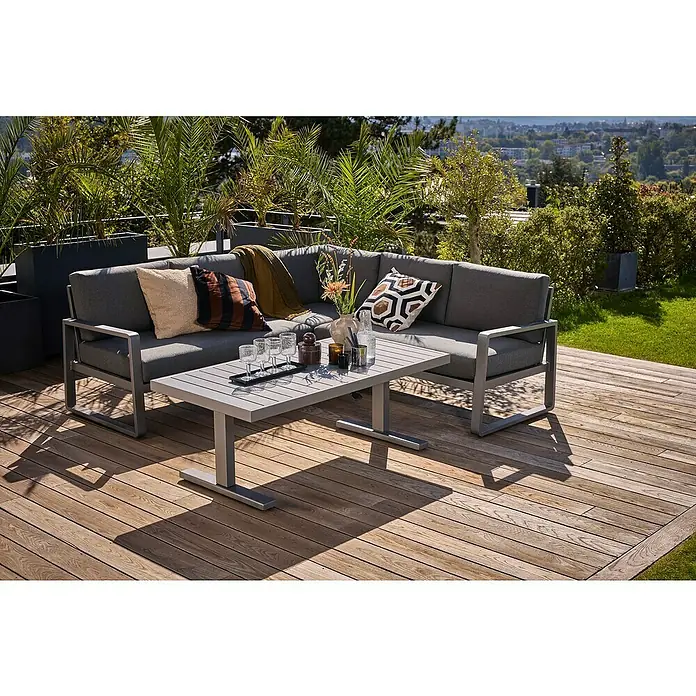 Sunfun Maja Loungemöbel-Set Ecklounge - 2 -tlg., Aluminium, Stahl, Olefin, Night-Grey - Stilvolles Gartenmöbel-Set mit grauem Ecksofa und passendem Tisch auf einer Holzterrasse, umgeben von üppigem Grün.