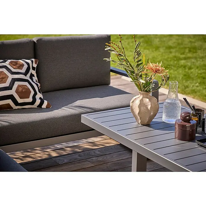Sunfun Maja Garten-Loungetisch - L x B x H: 138,5 x 70 x 72 cm, Stahl, Night-Grey - Nahaufnahme eines grauen Sofas mit Kissen und eines Tisches mit Vasen und dekorativen Gegenständen im Freien.
