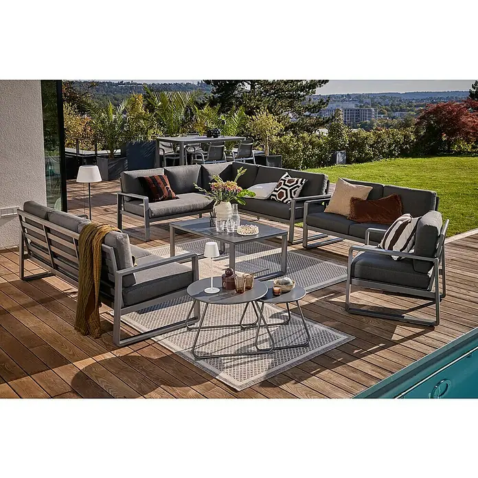 Sunfun Maja Loungemöbel-Set - 7 -tlg., Aluminium, Stahl, Sicherheitsglas Olefin, Night-Grey - Outdoor-Lounge-Set auf einer Holzterrasse mit grauen Möbeln, Kissen und einem Couchtisch, ideal für entspannte Stunden im Freien.