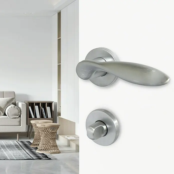 Diamond Doors Creative Zimmertürgarnitur WC Sunnyvale - Stärke Tür: 40 mm - 45 mm, Chrom matt, Schlitzkopf/Olive - Nahaufnahme eines modernen Türgriffs aus gebürstetem Stahl vor einem stilvollen Wohnzimmer.