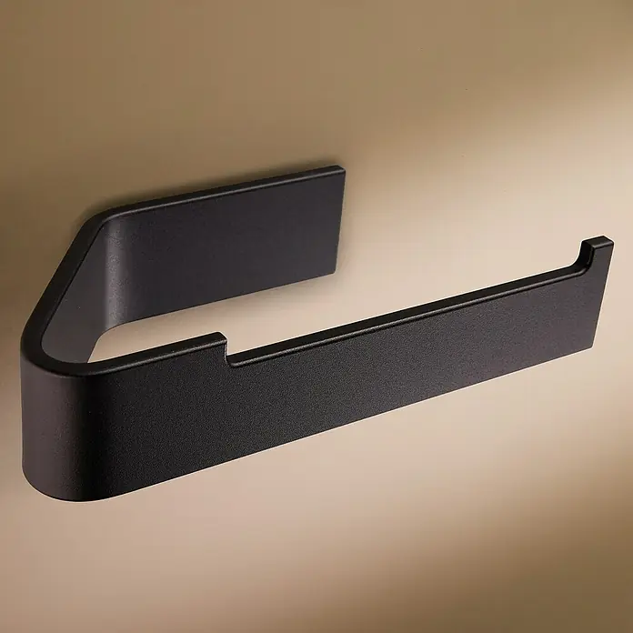 Designfabrik Hamburg Toilettenpapierhalter - Schwarz, Matt - Ein moderner, mattschwarzer Toilettenpapierhalter an einer beigen Wand montiert.
