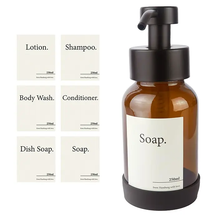 Designfabrik Hamburg Seifenspender - Edelstahl, Schwarz/Braunglas - Brauner Seifenspender mit schwarzen Details und verschiedenen Etiketten für Lotion, Shampoo, Spülmittel und Seife.
