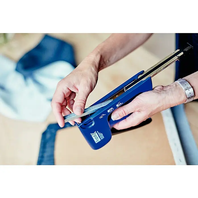 Rapid Handtacker Rapid R44 - Klammertiefe: 4 mm - 14 mm, Geeignet für: Flachdrahtklammern Nr. 140 - Nahaufnahme einer Person, die einen blauen Rapid-Tacker mit Klammern befüllt, um Stoffe zu befestigen.