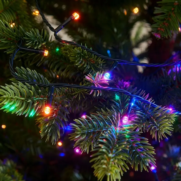 Tween Light LED-Lichterkette - Innen, Lichtfarbe: RGBW, Anzahl Leuchtmittel: 100 Stk., Netzbetrieben - Nahaufnahme einer Lichterkette mit bunten Lichtern, die einen Weihnachtsbaum schmücken und eine festliche Atmosphäre erzeugen.