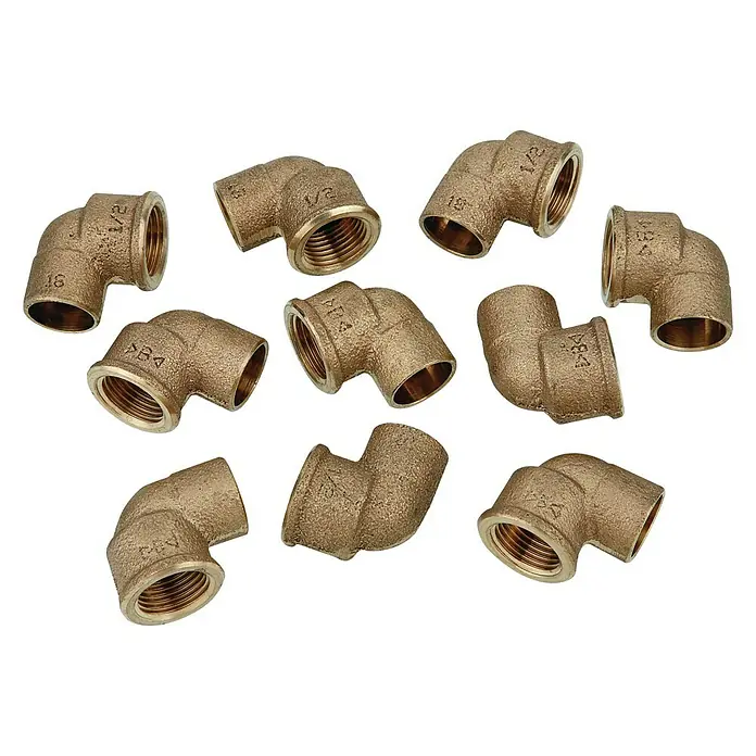 Winkel 4090g - Durchmesser: 18 mm, Innengewinde: ½″, 10 Stk., Rotguss - Nahaufnahme einer Gruppe von Messing-Rohrverbindungsstücken, die für Sanitärinstallationen verwendet werden und auf einem weißen Hintergrund angeordnet sind.