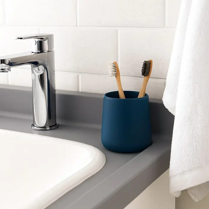 MSV Maonie Portacepillos - Ø x Al: 8,5 x 10 cm, Cerámica, Azul oscuro - Escena de baño con un vaso azul con dos cepillos de dientes, grifo y toalla blanca.