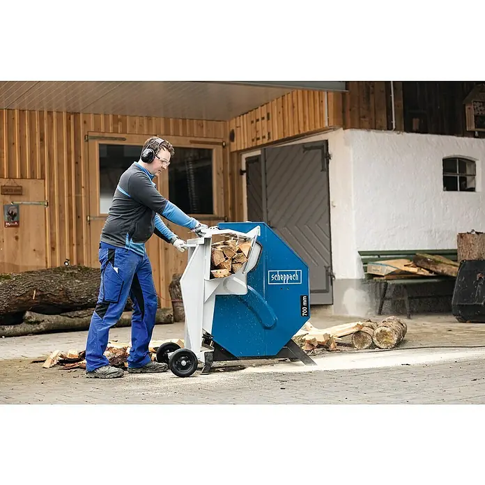 Scheppach Wippkreissäge HS730 - 4.500 W, Durchmesser Sägeblatt: 700 mm - Ein Mann bedient eine Scheppach Wippkreissäge 700 mm zum Schneiden von Holzscheiten. Der Bediener trägt Schutzkleidung und Kopfhörer.