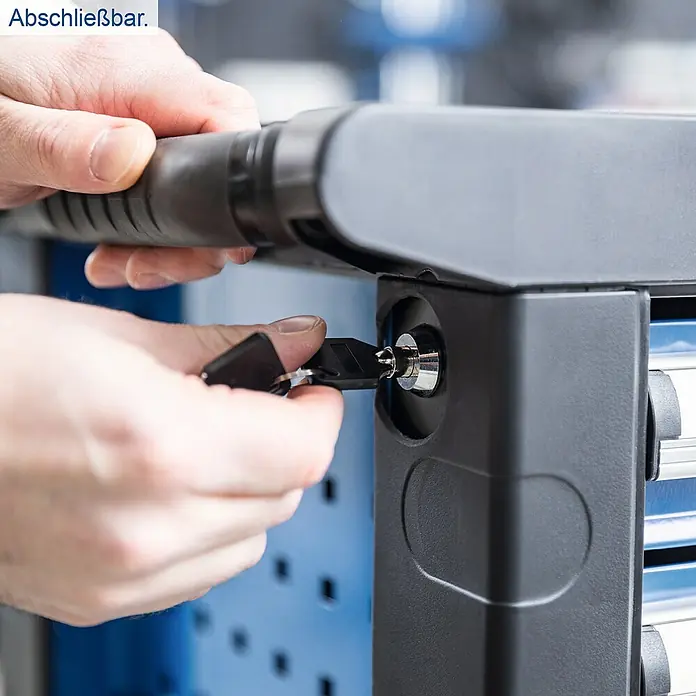 Scheppach Werkstattwagen TW 1150 - L x B x H: 760 x 460 x 965 mm, Anzahl Schubladen: 6 Stk., 70 -tlg. - Nahaufnahme eines abschließbaren Werkstattwagens mit einer Hand, die einen Schlüssel in das Schloss steckt.