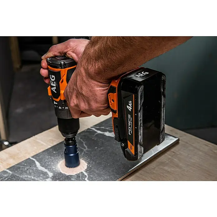 AEG Pro 18V Akku FORCE PROLITHIUM-ION™ - 4 Ah, Li-Ionen - Nahaufnahme einer AEG Bohrmaschine mit Lochsäge beim Bohren durch eine Fliese.