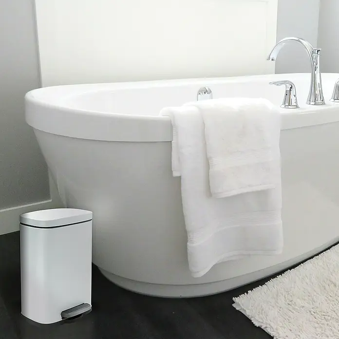 Spirella Cubo con pedal Akira - 5 l, Acero inoxidable, Blanco - Cubo de basura blanco con pedal al lado de una bañera con toallas. El cubo es delgado y moderno, perfecto para baños.