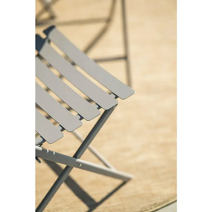 Garden Impressions Balkonmöbel-Set Alfa - 3 -tlg., Stahl, Taupe - Detailansicht eines grauen Klappstuhls mit Lattenrost vor einem hellen, unscharfen Hintergrund. Der Stuhl wirkt modern und minimalistisch.