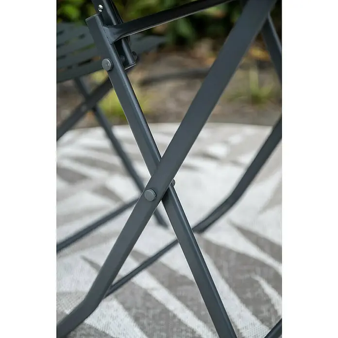 Garden Impressions Balkonmöbel-Set Alfa - 3 -tlg., Stahl, Schwarz - Detailaufnahme eines grauen Gartenstuhls, der auf einem gemusterten Teppich steht. Fokus auf die gekreuzten Metallbeine und deren Verbindung.