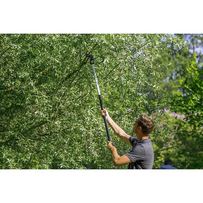 Fiskars Schneidgiraffe UPX82 - 166 cm, Max. Aststärke: 32 mm - Ein Mann benutzt eine Astschere mit Stiel, um Äste von einem Baum zu schneiden, wobei die Schere im Fokus steht.