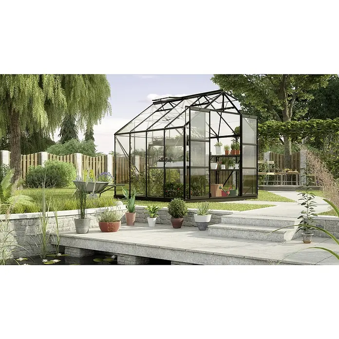 Vitavia Gewächshaus Uranus 6700 - Außenmaß inkl. Dachüberstand (B x T): 257 x 258 cm, 3 mm, Schwarz - Ein großes Gewächshaus mit Pflanzen und einem klaren Dach steht in einem gepflegten Garten mit einem Teich und einer Steinbrücke.