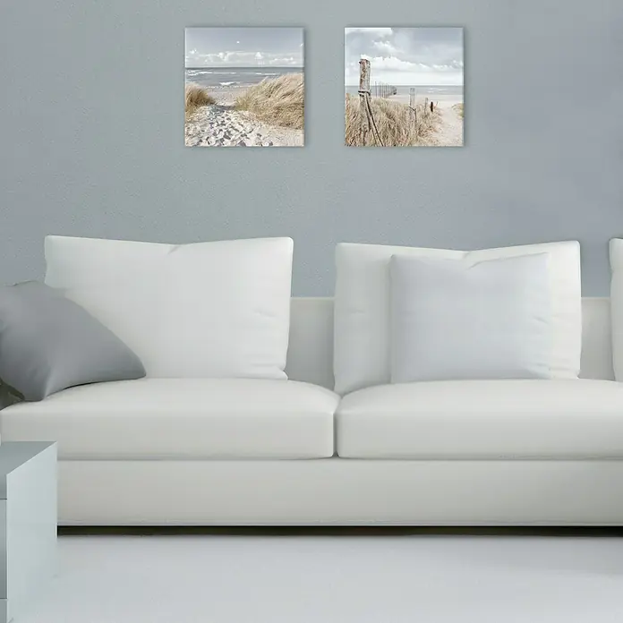 ProArt Maritime Glasbild - Oase der Sinne II, B x H: 20 x 20 cm - Wohnzimmerdekor mit zwei Strandbildern über einem weißen Sofa mit Kissen.