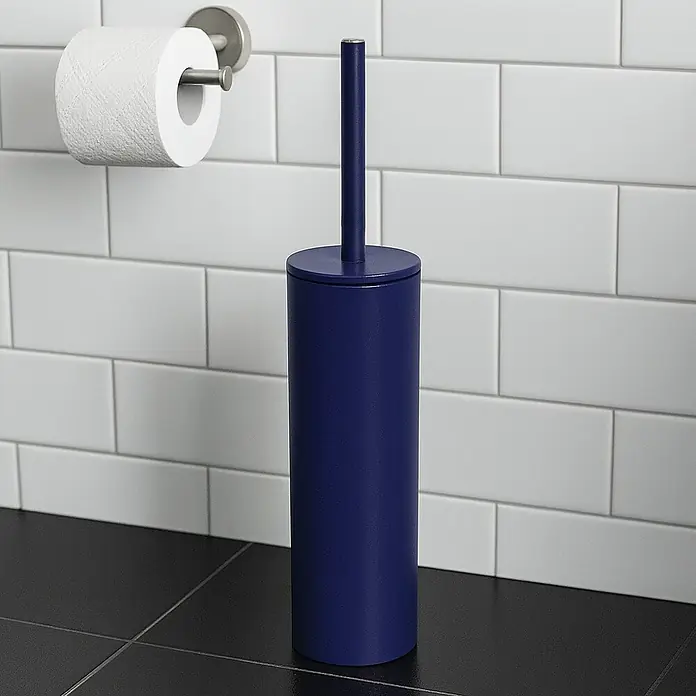Spirella Conjunto de escobilla Akira - 9,5 x 9,5 x 40 cm, Acero inoxidable, Azul marino - Un cepillo de baño azul con un soporte se encuentra al lado de un rollo de papel higiénico sobre un suelo negro. Perfecto para cualquier baño.
