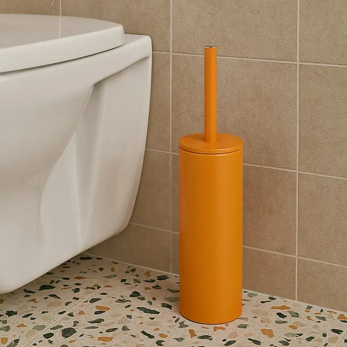 Spirella Conjunto de escobilla Akira - 9,5 x 9,5 x 40 cm, Acero inoxidable, Naranja - Un escobillero naranja junto a un inodoro blanco en un baño con suelo de terrazo.