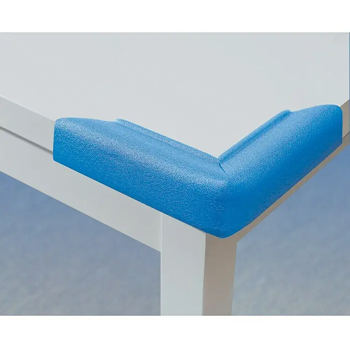 Nips Schaumstoffkantenschutz - Länge: 4 m, Polyethylen - Nahaufnahme eines blauen Eckenschutzes auf einem weißen Tisch, der für Kindersicherheit sorgt und Verletzungen verhindert.