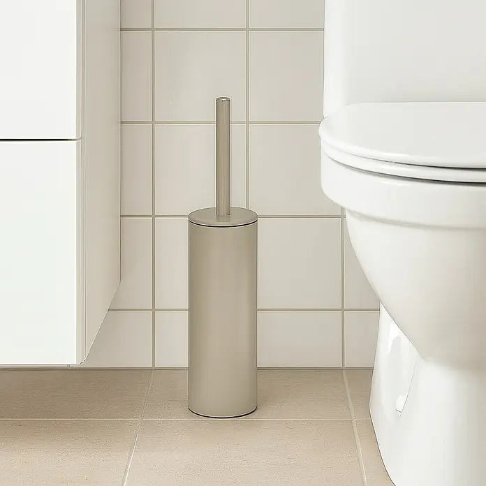 Spirella Conjunto de escobilla Akira - 9,5 x 9,5 x 40 cm, Acero inoxidable, Taupe - Un elegante cepillo de baño gris se encuentra junto a un inodoro blanco en un baño con azulejos claros.