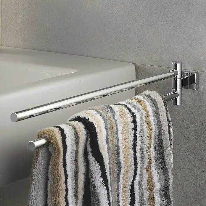 Grohe Essentials Cube Handtuchhalter - 2-armig, Chrom, Glänzend - Ein moderner, doppelter Handtuchhalter aus Chrom mit einem gestreiften Handtuch, montiert an einer grauen Wand neben einem weißen Waschbecken.