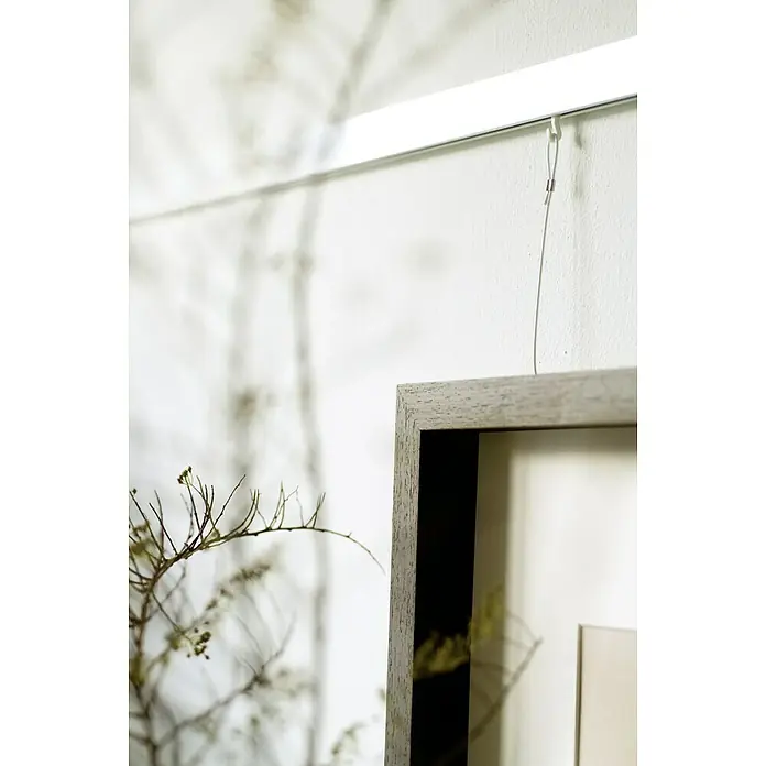 Nielsen Galerieschiene Profi - Länge: 1,5 m, Weiß - Nahaufnahme eines gerahmten Bildes, das an einer weißen Wand mit einem modernen Aufhängungssystem befestigt ist. Die elegante und minimalistische Gestaltung betont das Kunstwerk.