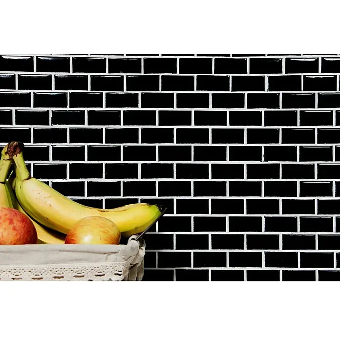 Mosaikfliese Brick Bond Diamond CBB 108 - 30 x 30 cm, Schwarz, Glänzend - Nahaufnahme eines Korbs mit Bananen und Äpfeln vor einer Wand aus schwarzen Metrofliesen mit weißen Fugen.