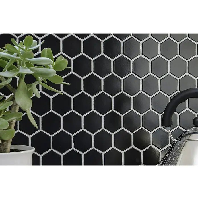 Mosaikfliese Hexagon Uni HX 090 - 32,5 x 28,1 cm, Schwarz, Glänzend - Nahaufnahme von schwarzen sechseckigen Fliesen mit weißem Fugenmörtel, die eine stilvolle und moderne Wand bilden.