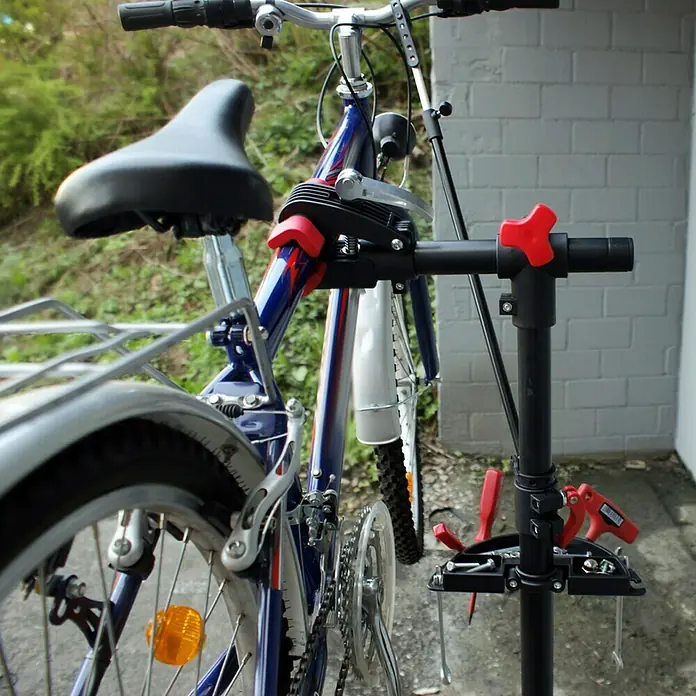 Eufab Fahrradmontageständer PROFI - Geeignet für: Rahmenstärke 2,5 - 4 cm, Nutzlast: 30 kg - Ein Fahrrad ist an einem Reparaturständer befestigt, der das blaue und silberne Fahrrad mit rotem Akzenten hält. Ideal für Reparaturen und Wartung.