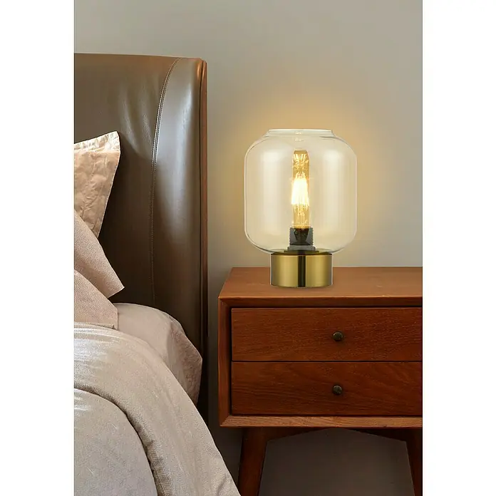 Lámpara de sobremesa redonda - 40 W, Ø x Al: 20 x 70 cm, Ámbar, E27 - Este primer plano muestra una lámpara de noche con una pantalla de cristal transparente y una bombilla decorativa, colocada sobre una mesita de noche de madera.