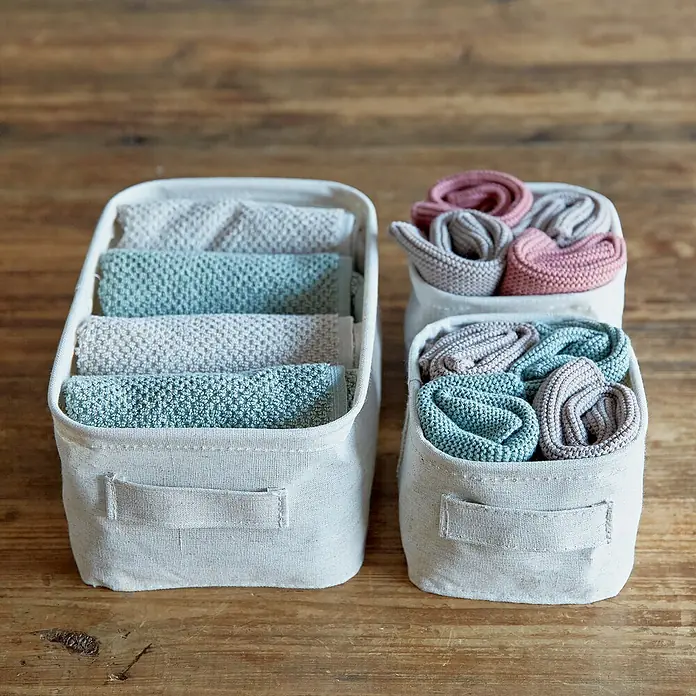 Store It Premium Bad-Aufbewahrungskorb - 26 x 16 x 12 cm, Naturfaser, Beige - Drei Stoffkörbe mit ordentlich gefalteten und gerollten Textilien in verschiedenen Farben auf einem Holztisch.
