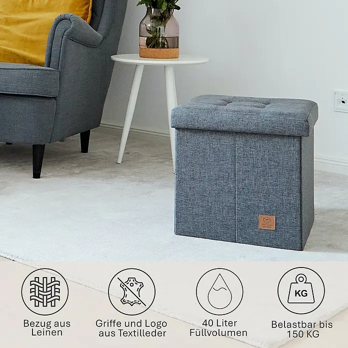Store It Premium Hocker mit Stauraum Home - L x B x H: 38 x 38 x 38 cm, Grau - Das Bild zeigt einen grauen faltbaren Hocker mit Stauraum, der bis zu 150 kg belastbar ist, neben einem Sessel und einem Tisch.