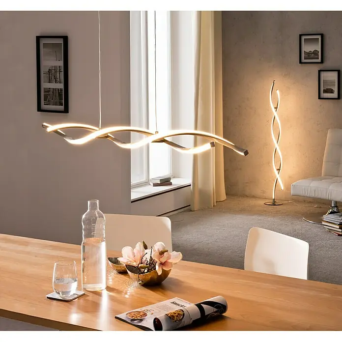 Paul Neuhaus Polina LED-Pendelleuchte - Warmweiß - Modernes Esszimmer mit einer wellenförmigen LED-Hängeleuchte über dem Holztisch und einer passenden Stehleuchte im Hintergrund.