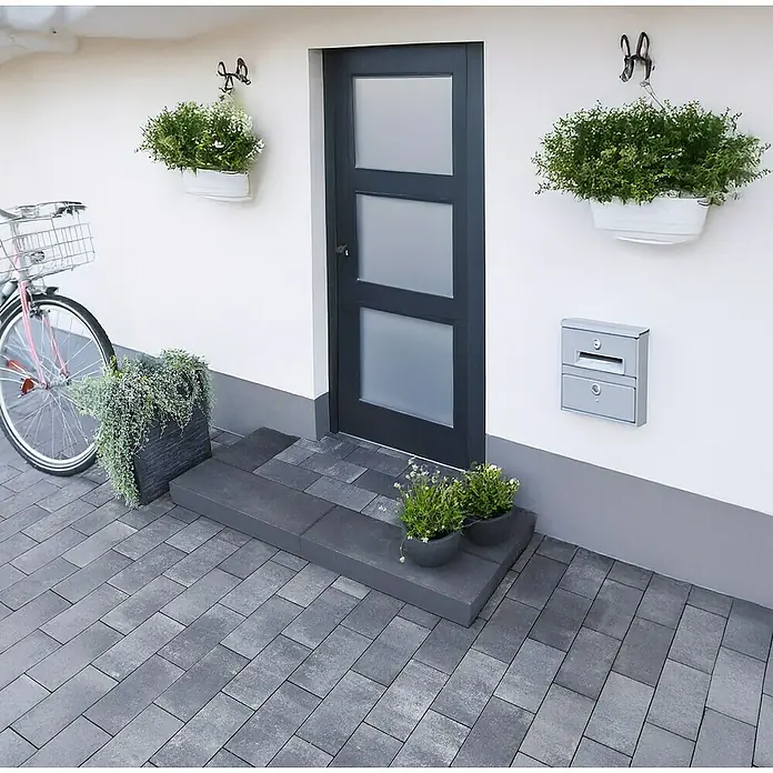 EHL Pflasterstein Cortona Flair - 40 x 20 x 8 cm, Grau-Anthrazit, Beton - Eingangsbereich eines Hauses mit grauer Tür und Pflastersteinen, dekoriert mit Pflanzen und einem Fahrrad.