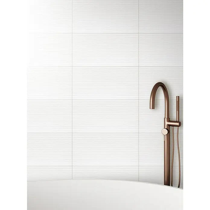 DryTile Wandfliese Palazzo Strukturiert Linie - 30 x 60 cm, Weiß, Matt - Das Bild zeigt eine moderne freistehende Badewannenarmatur in Kupferoptik vor einer weißen, horizontal strukturierten Wand, die für ein elegantes Badezimmerdesign steht.