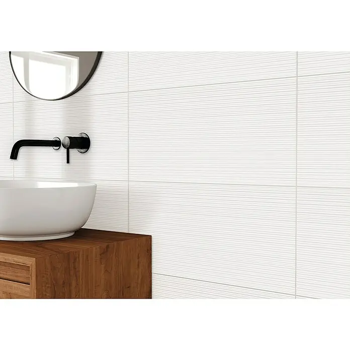 DryTile Wandfliese Palazzo Strukturiert Rille - 30 x 60 cm, Weiß, Glänzend - Nahaufnahme eines Waschbeckens mit Armatur und Spiegel vor einer Wand mit weißen, horizontal geriffelten Fliesen.