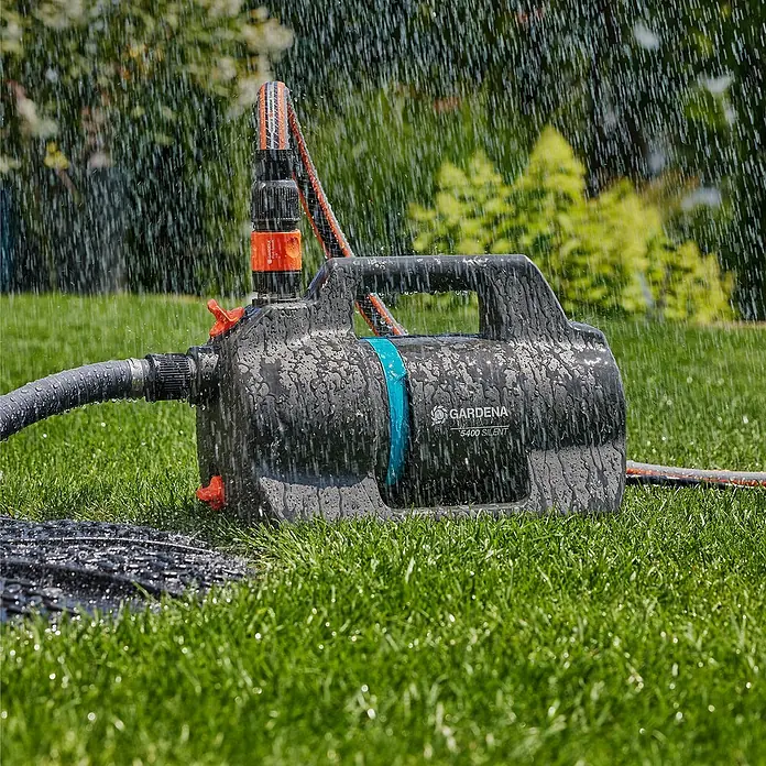 Gardena Gartenpumpe 5400 Silent - 650 W, Max. Fördermenge: 5.400 l/h - Gardena 5400 Silent Gartenpumpe in Aktion, umgeben von üppigem Grün und fallendem Wasser.