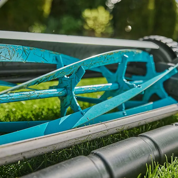 Gardena Spindelmäher Plus 400 - Schnittbreite: 40 cm - Nahaufnahme eines Rasenmähers mit blauen Klingen, der auf dem grünen Rasen steht und bereit ist, die Arbeit zu erledigen.