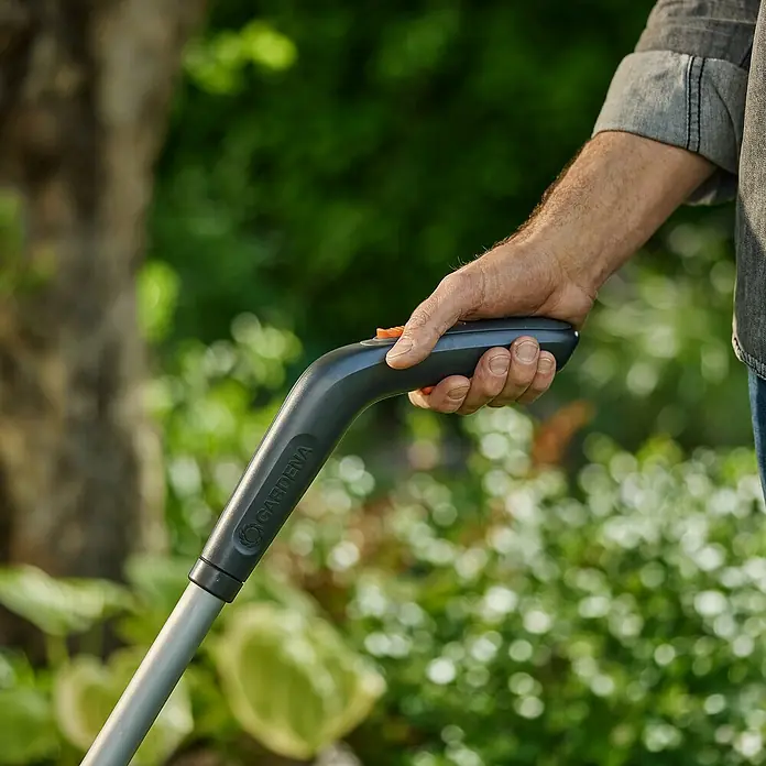 Gardena Teleskopstiel - 2 -tlg., Passend für: Gardena Power for All 18V Akku-Gras- & Strauchschere 20/18V - Detailaufnahme einer Hand, die einen Gardena-Gerätegriff hält. Fokus liegt auf Ergonomie und Design des Gartenwerkzeugs.