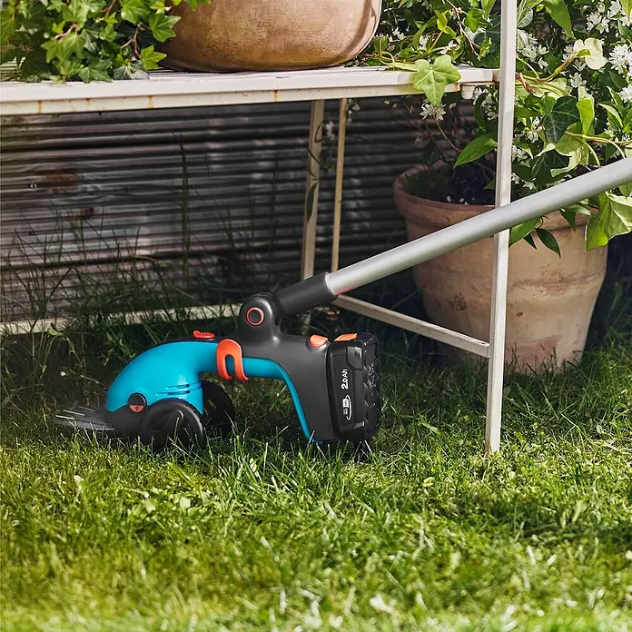 Gardena Power for All 18V Akku-Grasschere PowerCut 20/18V - 18 V, Ohne Akku - Rasentrimmer mit Akku zum Schneiden von Gras unter einem Regal mit Töpfen, ideal für präzise Gartenarbeit.
