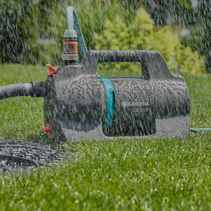 Gardena Gartenpumpe 5000 Silent - 550 W, Max. Fördermenge: 5.100 l/h - Gardena 5000 Silent Hauswasserautomat im Einsatz. Die Pumpe ist mit Schläuchen verbunden und steht im Grünen.