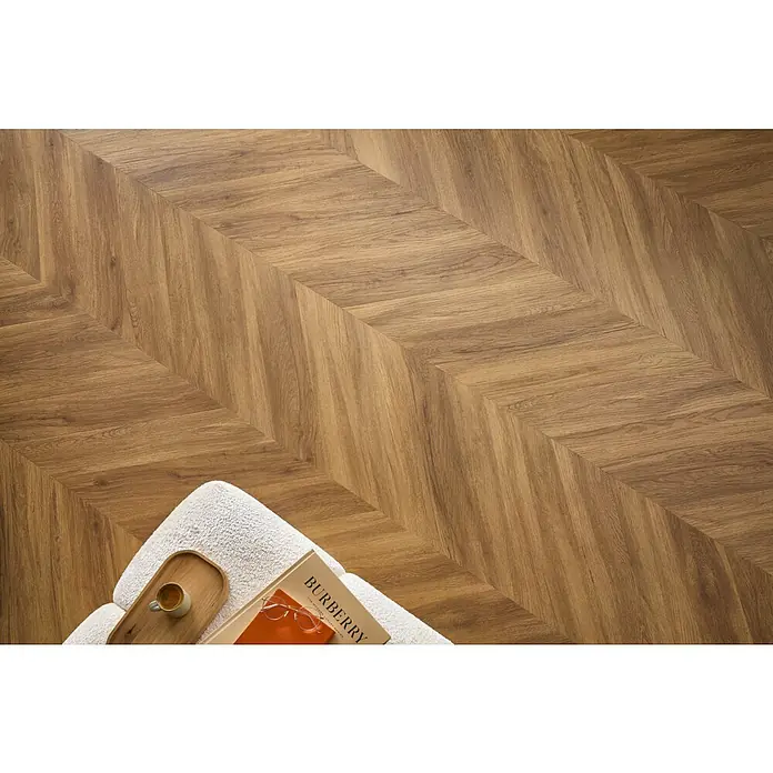 Vinylboden SPC Chevron - Jersey Eiche, 120 x 600 x 4,5 mm - Einladende Aufnahme von Chevron-Parkett in warmen Holztönen, das eine gemütliche und stilvolle Atmosphäre vermittelt.