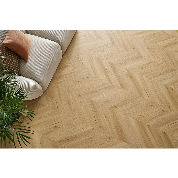 Vinylboden SPC Chevron - Arvada Eiche, 120 x 600 x 4,5 mm - Helle Holzböden im Fischgrätmuster schaffen ein warmes und einladendes Ambiente im Raum. Das Sofa und die Pflanze ergänzen das Dekor.