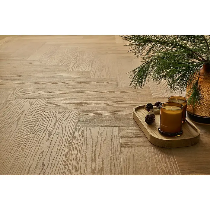 Vinylboden SPC Herringbone - Garda Eiche, Fischgrät, 148 x 592 x 4,5 mm - Nahaufnahme eines hellen Holzfußbodens mit einem rustikalen Tablett mit Kerzen, Tannenzapfen und einem dekorativen Zweig in einer Vase.