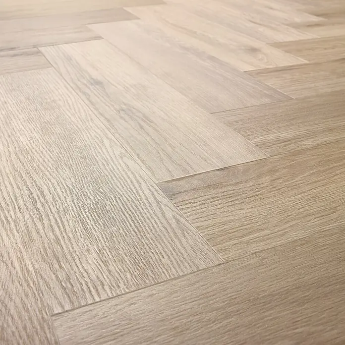 Vinylboden SPC Herringbone - Tucson Eiche, Fischgrät, 148 x 592 x 4,5 mm - Nahaufnahme von hellem, modernem Fischgrätparkett. Das Muster und die Holzstruktur verleihen dem Boden ein elegantes und stilvolles Aussehen.