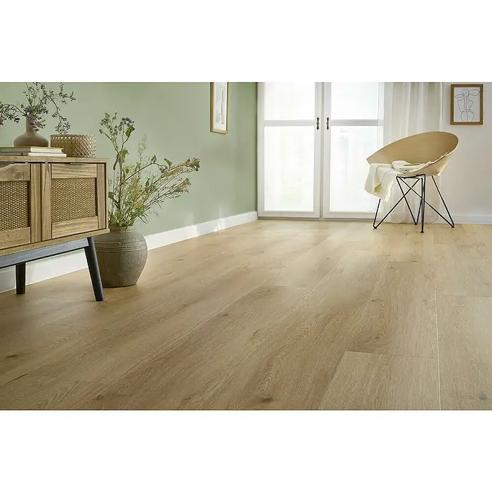 Vinylboden SPC XL - Eiche Arvada, Landhausdiele, 1.511 x 229 x 6,3 mm - Detailaufnahme eines Interieurs mit hellem Holzboden, einem Holzschrank und einem Design-Stuhl vor einem Fenster. Der Bodenbelag ist ein echter Hingucker.